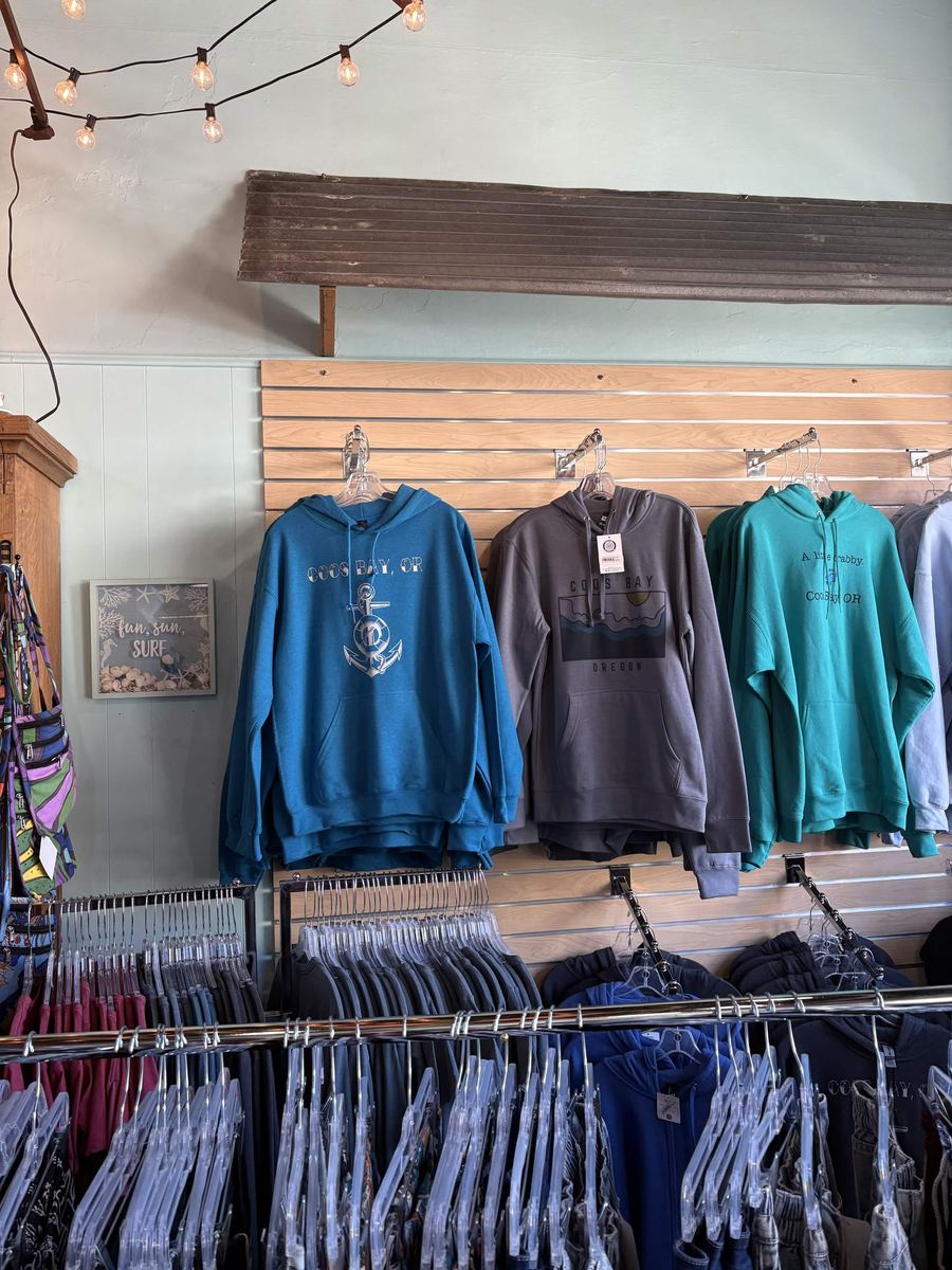 Wall of Coos Bay Oregon hoodies in teal, grey, and black