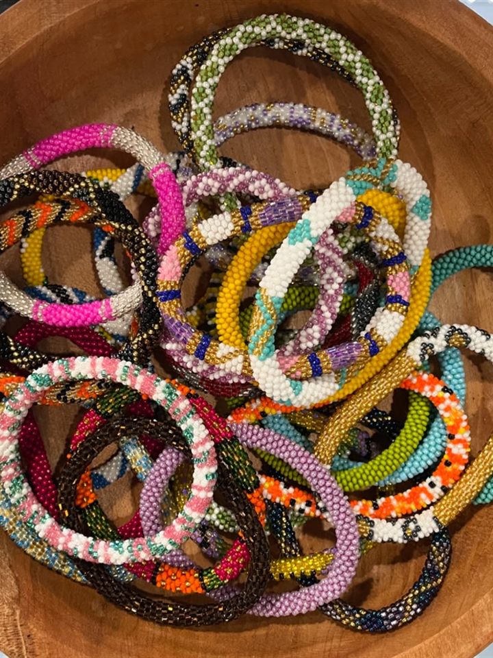 Wooden bowl full of colorful rolled glass seed bead bracelets