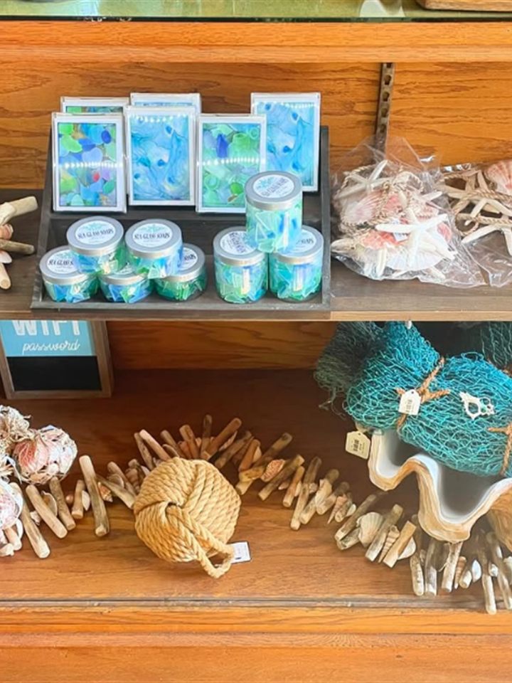 Shelf of sea glass soaps, driftwood, rope knots, starfish, and a decorative fishing net