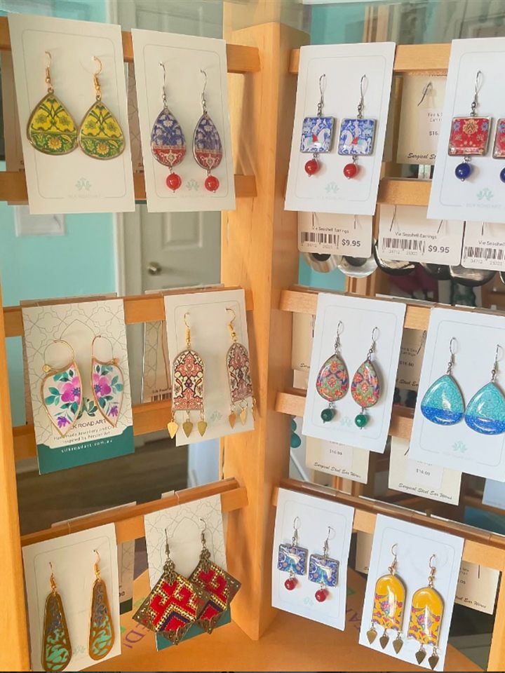 Wooden rack of colorful hand made art print earrings on cards