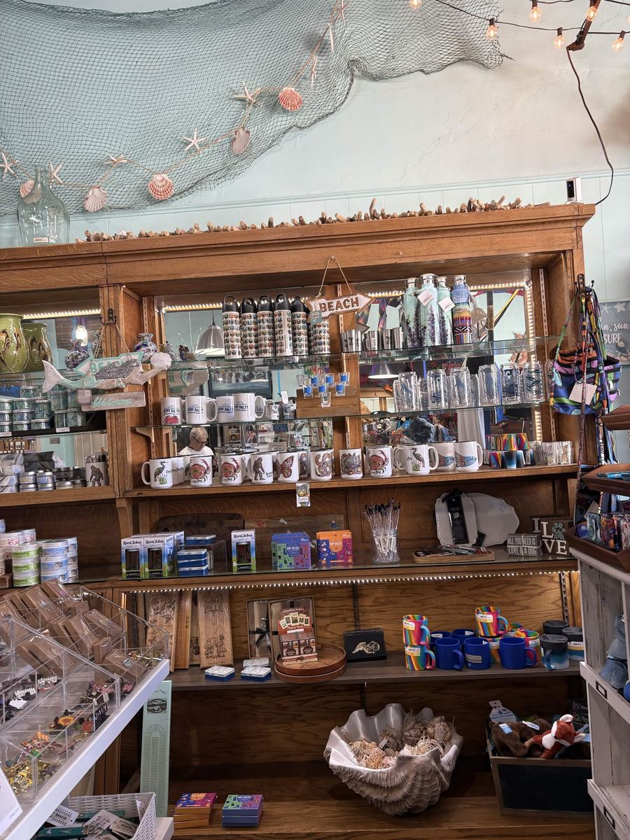 Oak hutch displaying Coos Bay and Stay Salty mugs, tumblers, and coastal drinkware