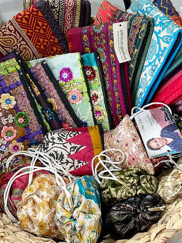 Basket of colorful zip pouches and drawstring bags sewn from recycled sari fabric